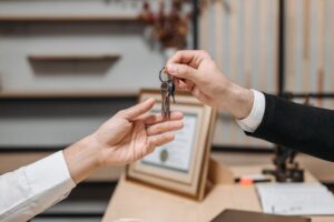 Some handing the keys of a house to another person in a law office