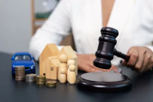 Judge hitting gavel with house family car and coins on table, legal decision and property